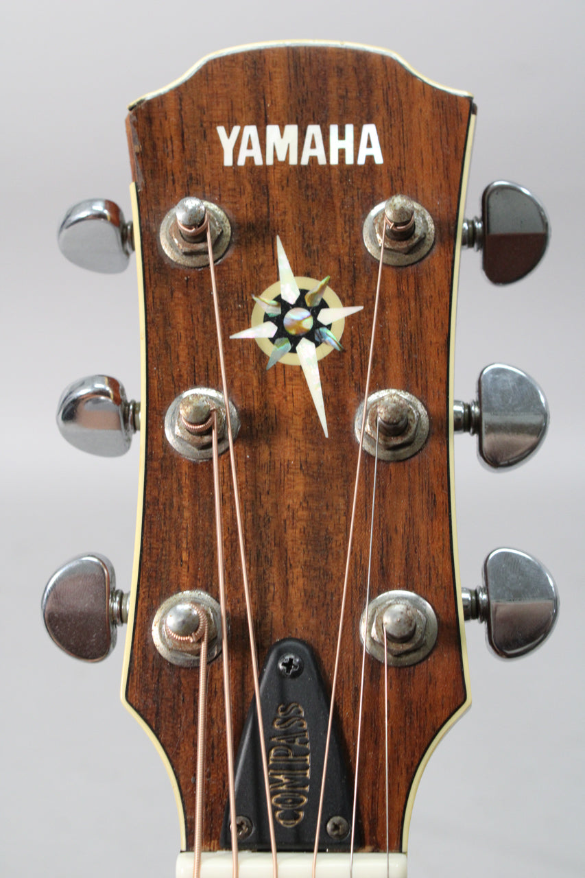 Close-up of the dark wood headstock with a mother-of-pearl compass inlay, chrome tuners, and a black truss rod cover.