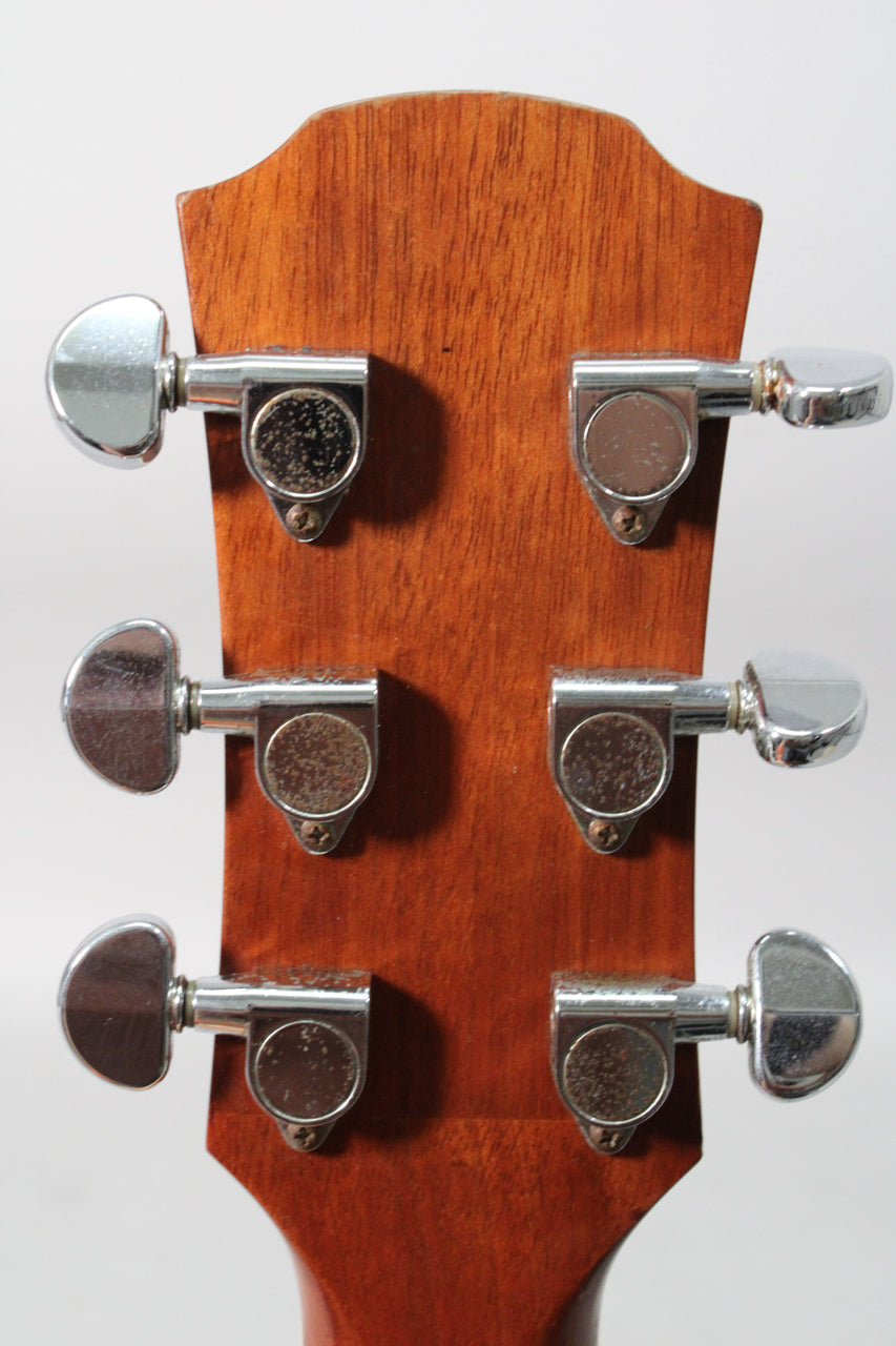 The back of a mahogany headstock with six chrome tuners, showing some pitting and wear on the tuner buttons.