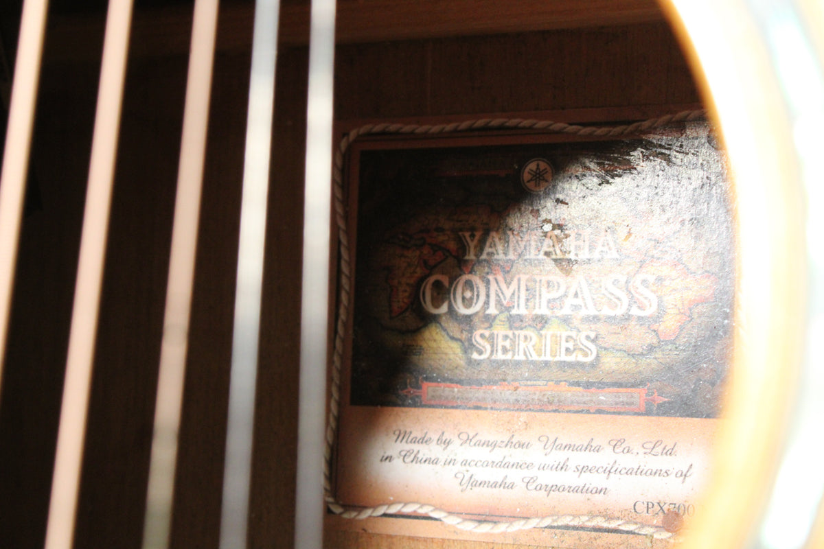 A close-up inside the soundhole reveals the label, framed by rope-like binding, with visible wear and dust on the dark, map-like graphic.