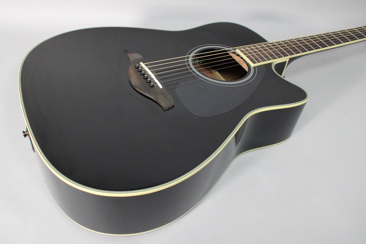 The black gloss acoustic-electric guitar is angled from the upper bout, showing the soundhole, pickguard, bridge, and cutaway.