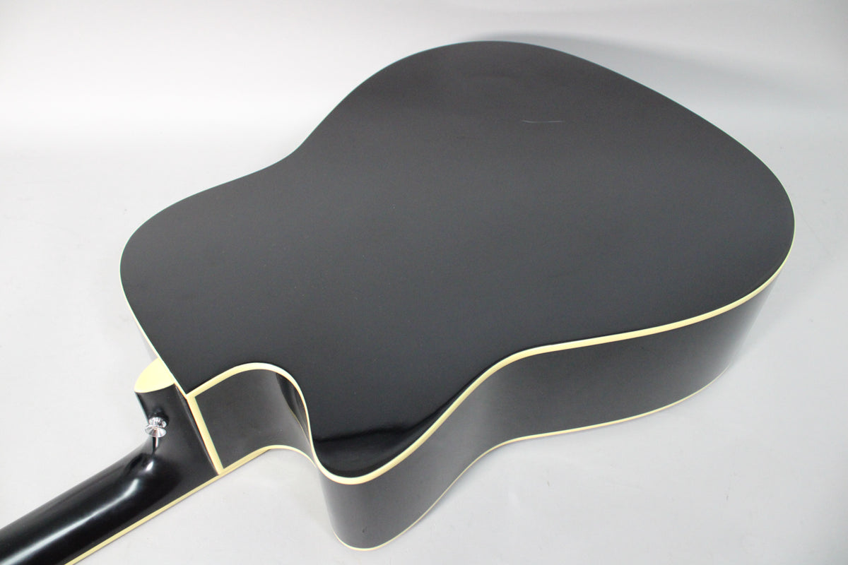 The back of a black acoustic guitar with a matte finish, showing a cutaway and cream binding, with a strap button on the neck heel.