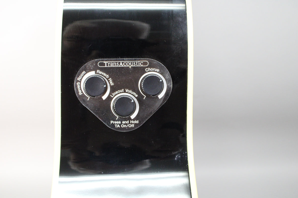 Close-up of the guitar's black side, showing the TransAcoustic control panel with three black knobs for Reverb, Chorus, and Volume.