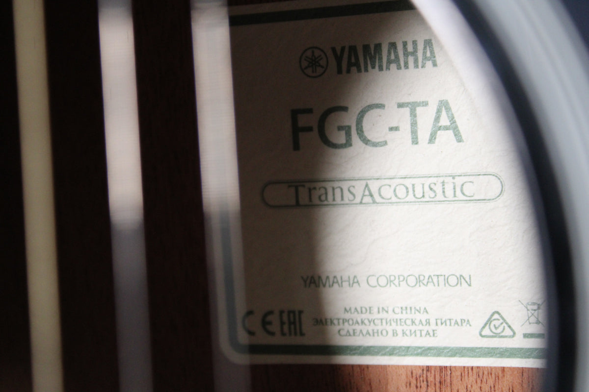 The guitar's soundhole label is visible, showing text and logos, with vertical light stripes across the dark wood interior.