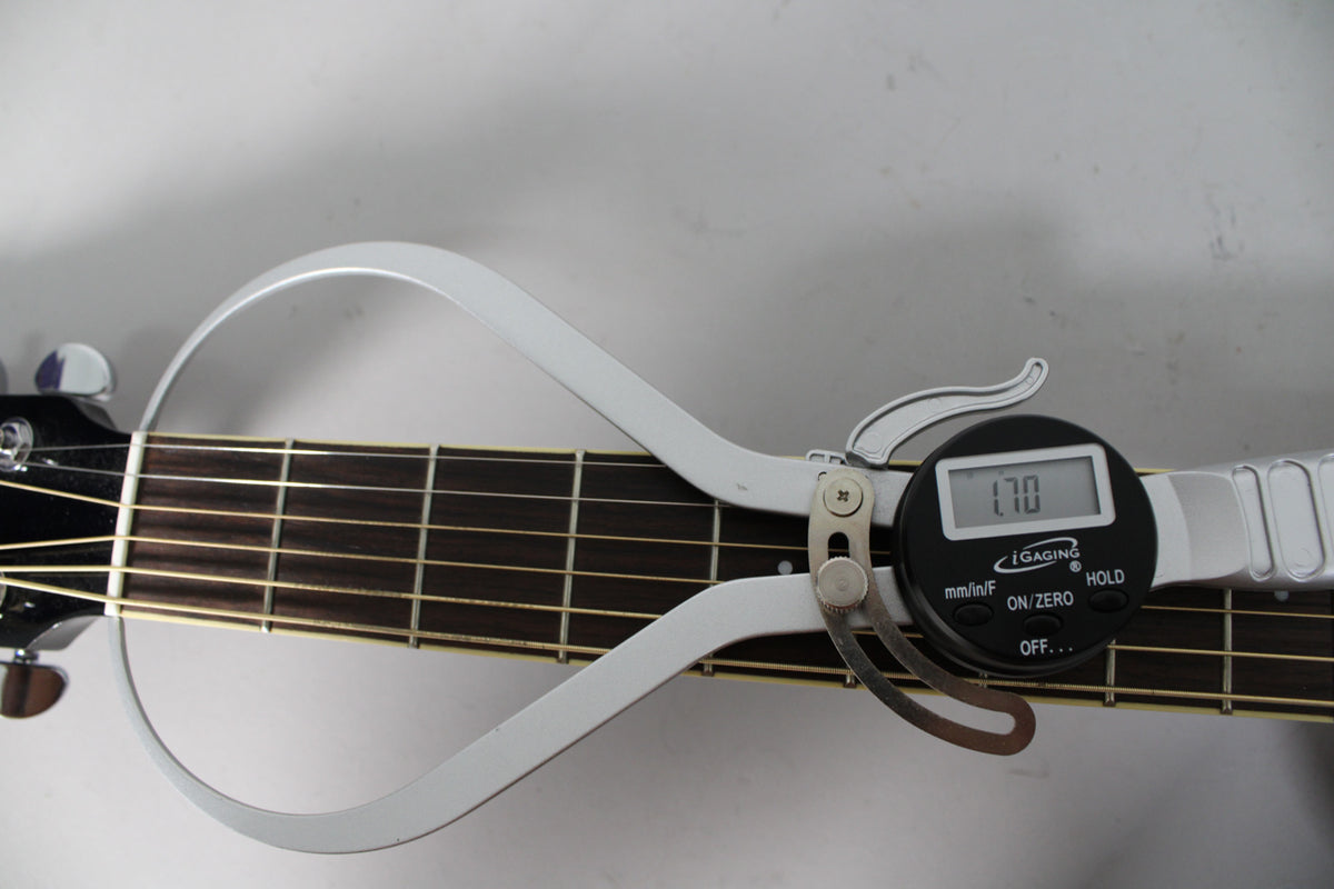 A digital caliper measures the guitar's fretboard width at 1.70 inches, with the headstock and tuning pegs visible on the left.