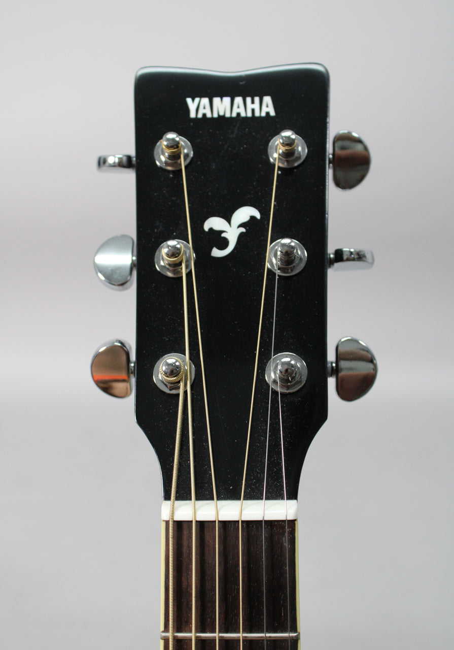 The guitar's black headstock, with a white logo and tuning fork emblem, features six chrome tuners and a white nut.