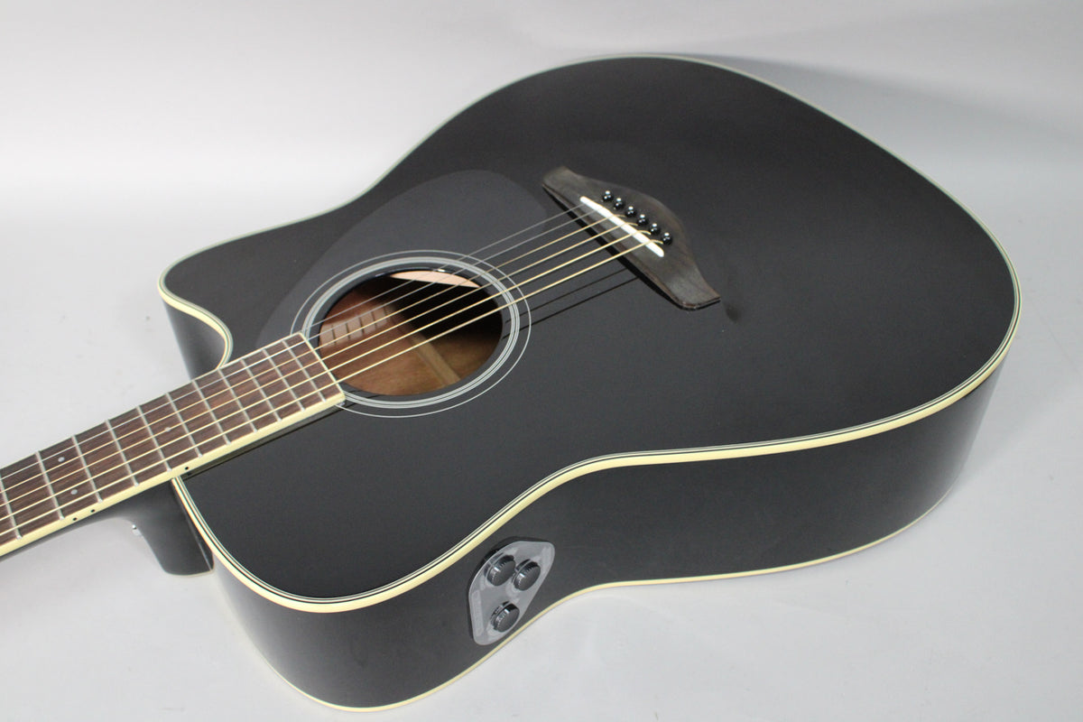 The black matte acoustic-electric guitar is angled from the upper left, showing its cutaway, soundhole, bridge, and three chrome control knobs.