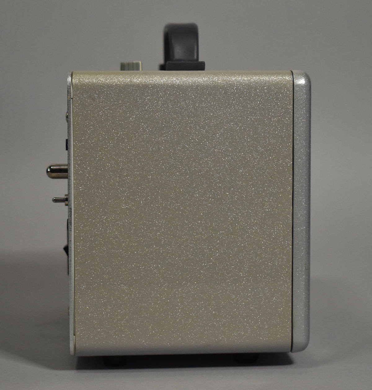 Right side view of a compact, rectangular amp with a sparkly champagne finish and silver trim, showing a black handle on top.