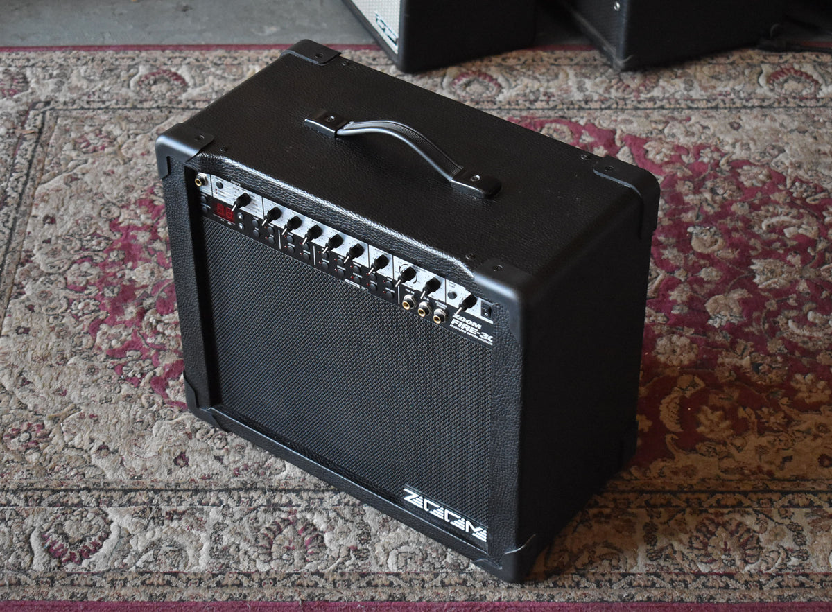 A black textured combo amp, viewed from the front-right, with a top handle and a row of silver knobs and red digital display.