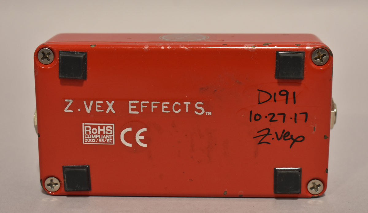 The red pedal's bottom is visible, showing four black rubber feet, four silver screws, and white text with a handwritten date.