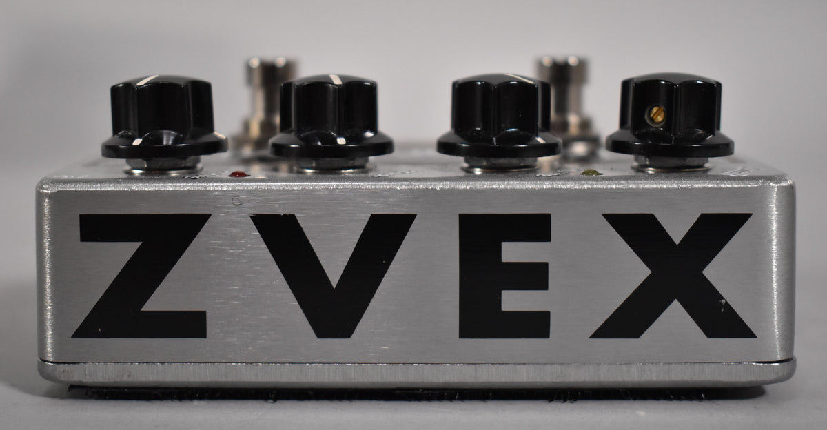 The silver brushed metal pedal is shown from the front, with four black control knobs and a large black "ZVEX" logo.