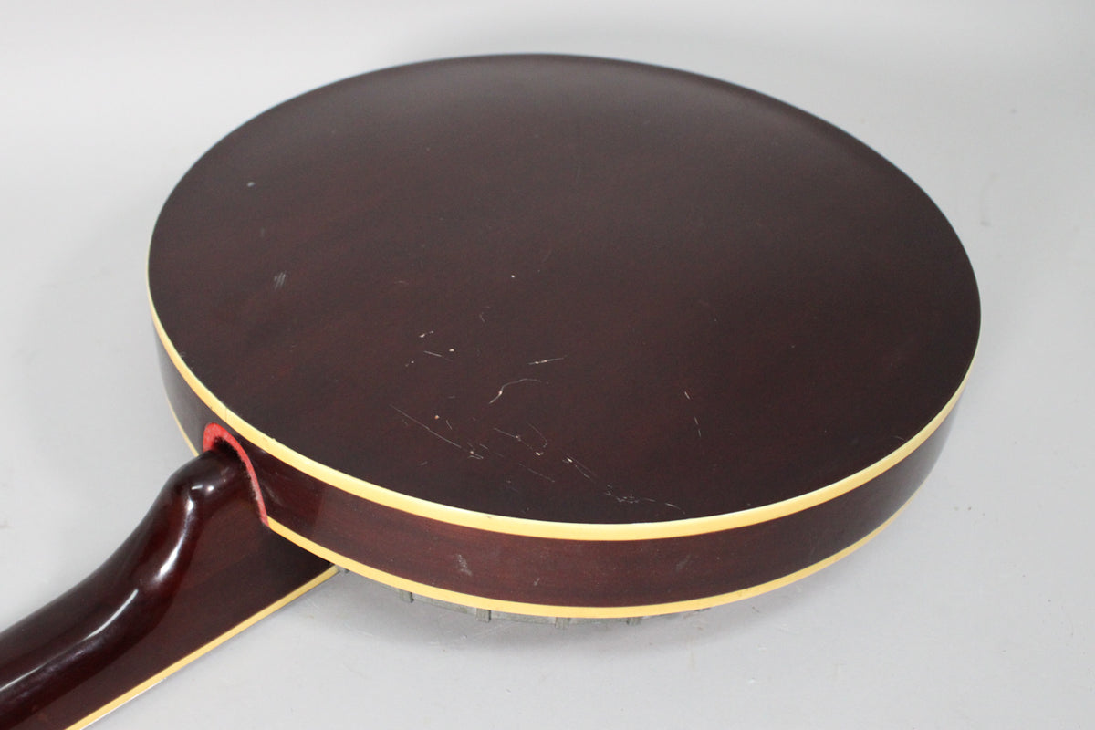 The dark brown banjo resonator back and side are visible, with cream binding and many surface scratches.