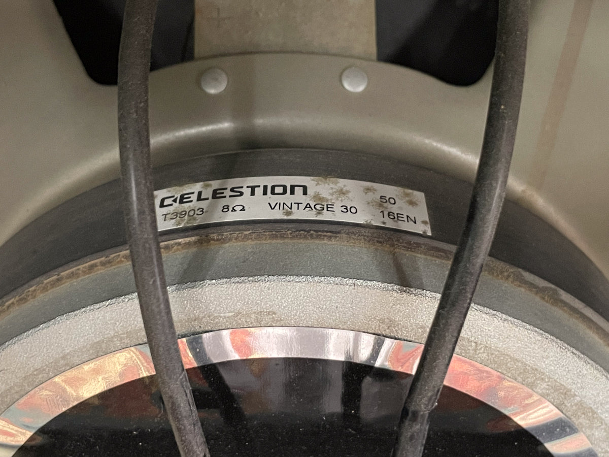 Close-up of a speaker's silver frame and black cone, with a white label showing "Celestion" and "Vintage 30" partially visible.