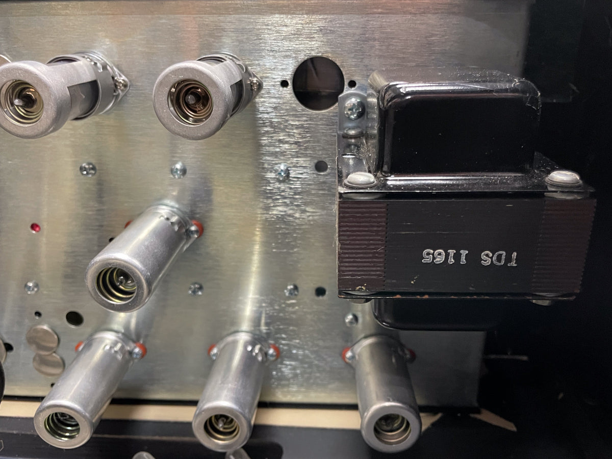 Close-up of the amp's brushed metal chassis, showing four silver tube sockets and a black transformer with visible screw heads.