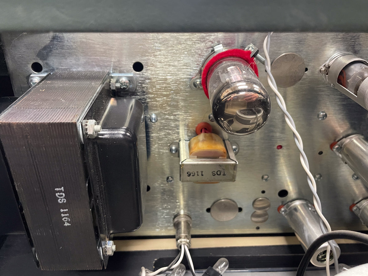 Close-up of the amp's brushed metal chassis, showing a large transformer, several vacuum tubes, and wiring.