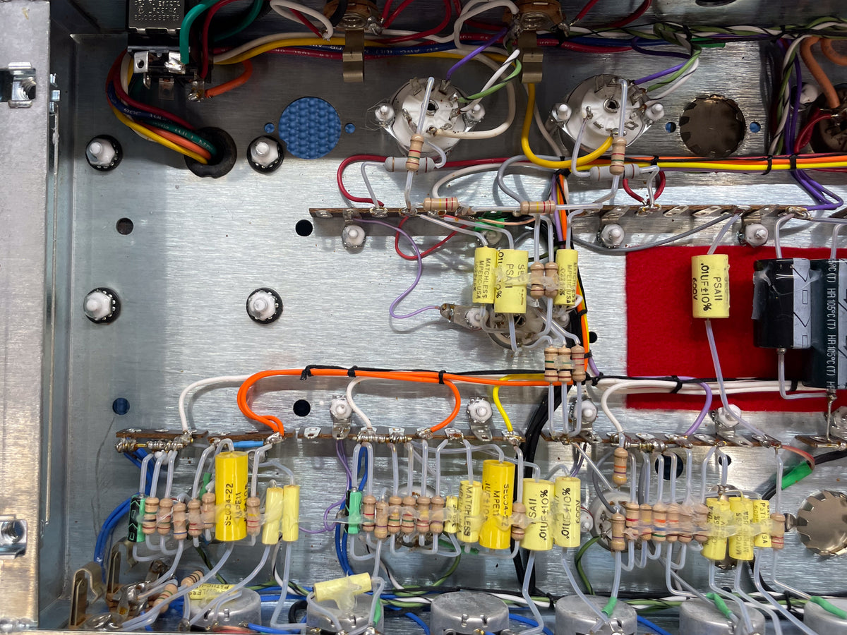 Close-up of the amp's internal wiring, showing numerous resistors, capacitors, and colorful wires on a brushed metal chassis.