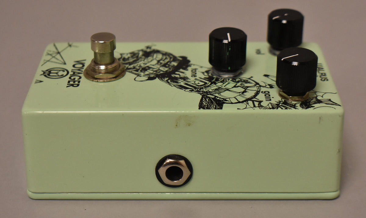 The green effect pedal is angled from the right, showing the input jack on the front, a footswitch, and three black control knobs.