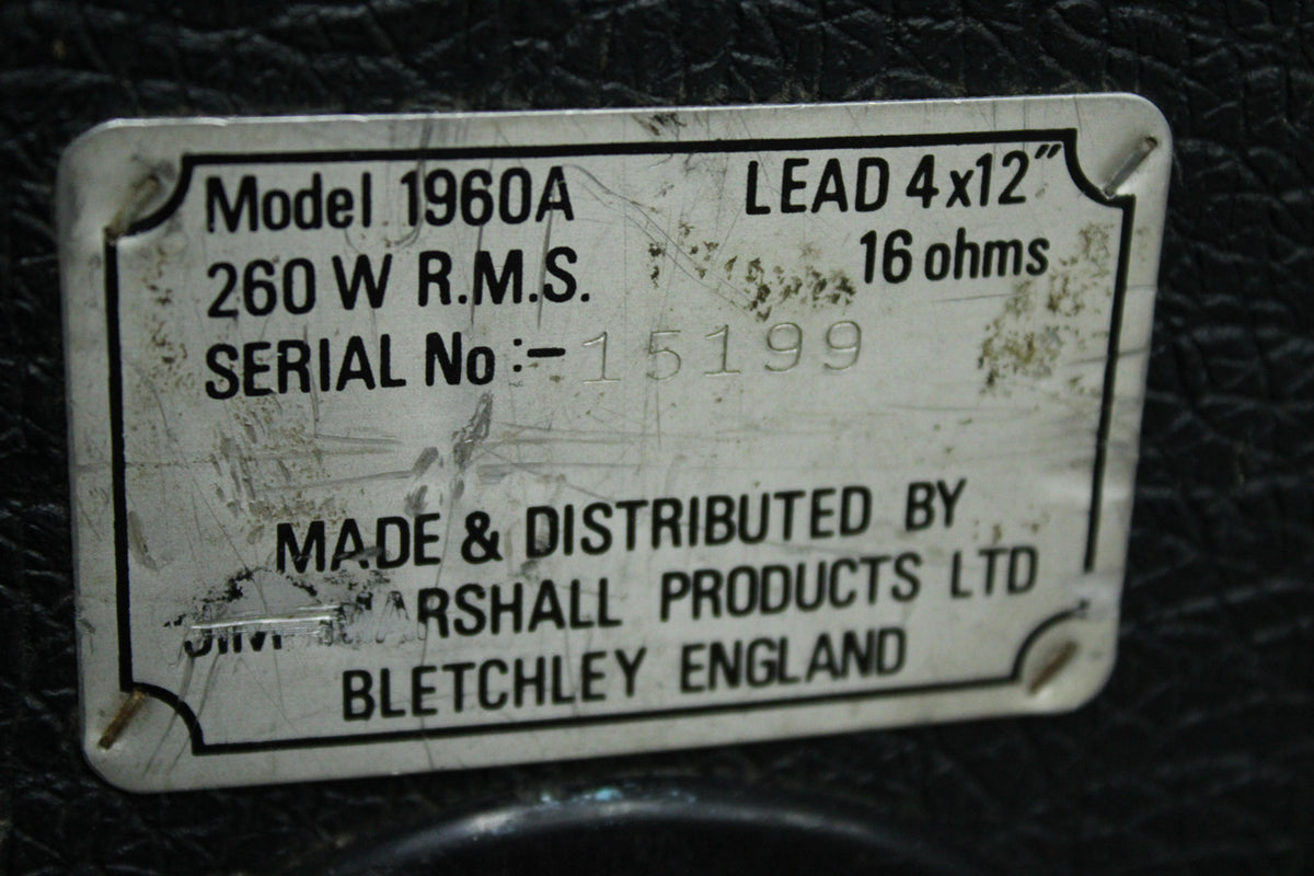 Close-up of the silver metal serial plate on the black textured cabinet, showing scratches and wear.