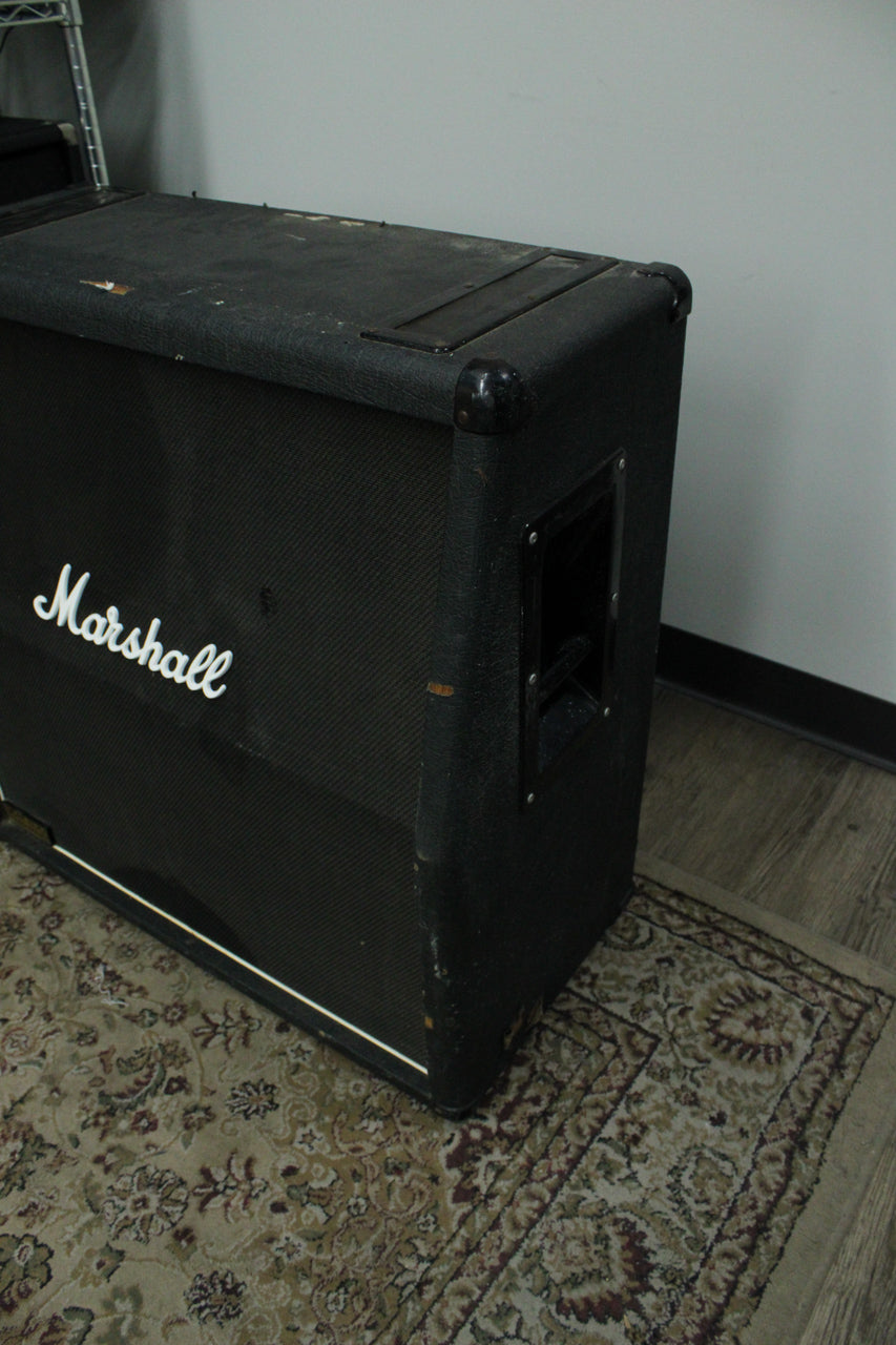 The black textured cabinet is angled, showing the front grille with white script logo, side handle, and worn top surface.