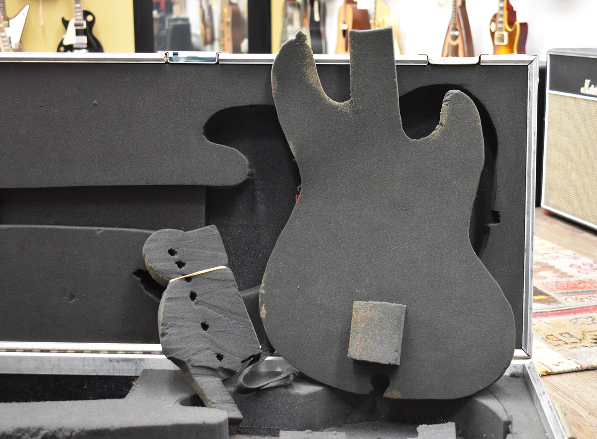 Open flight case with a black foam interior, showing a J Bass/StingRay body cutout and a separate headstock cutout.