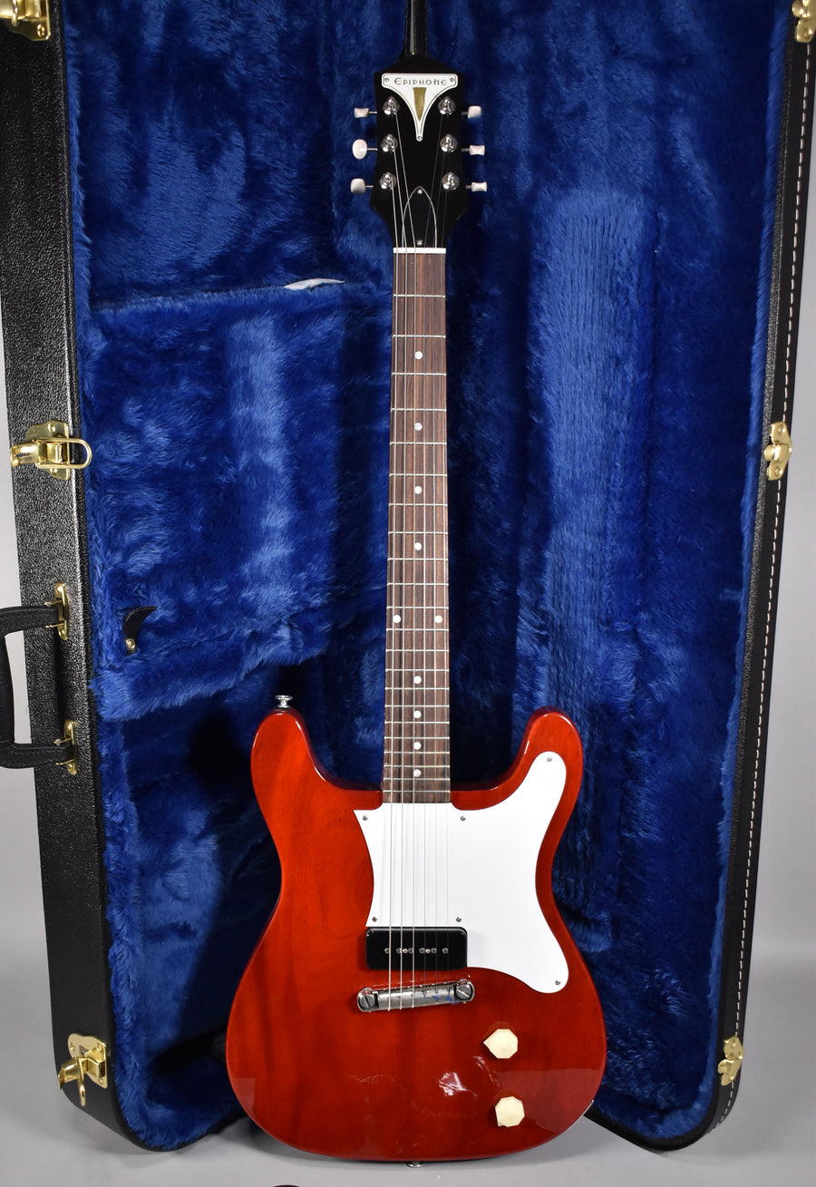 Full-length view of a glossy cherry red electric guitar with a white pickguard, single P90 pickup, and two cream knobs, in a blue-lined case.