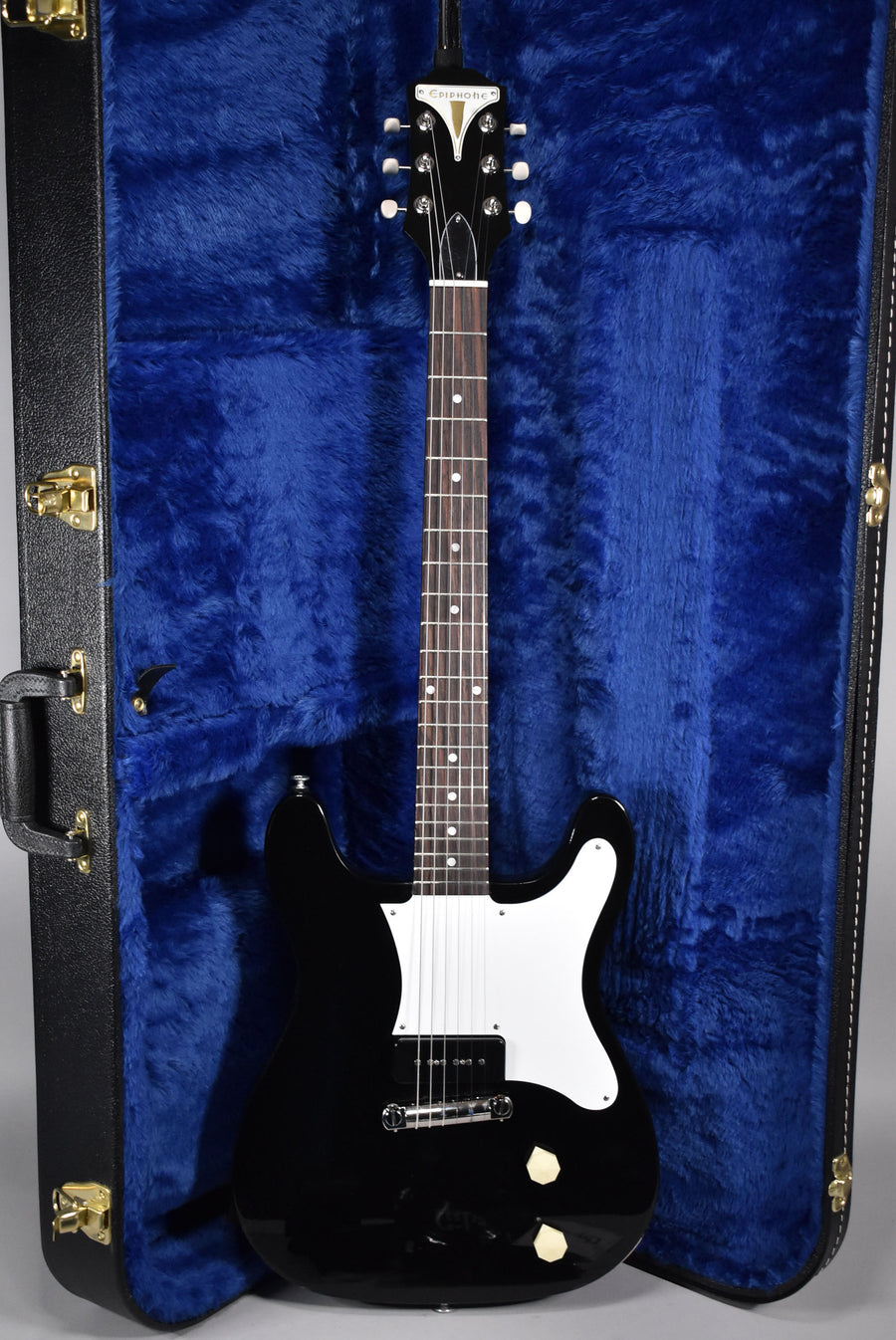 Full-length view of a glossy black electric guitar with a white pickguard, a single black P90 pickup, and two cream control knobs, resting in a blue fur-lined case.