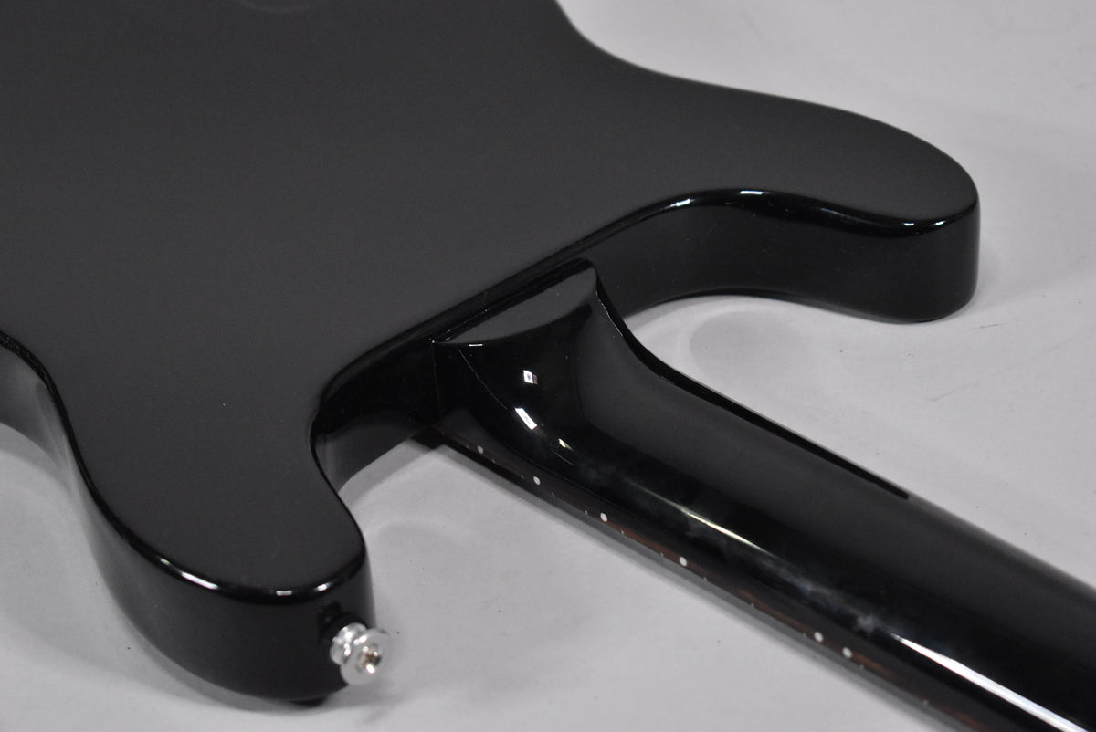 The guitar's back, with a matte black body and glossy neck, shows the neck joint and a chrome output jack on the lower bout.