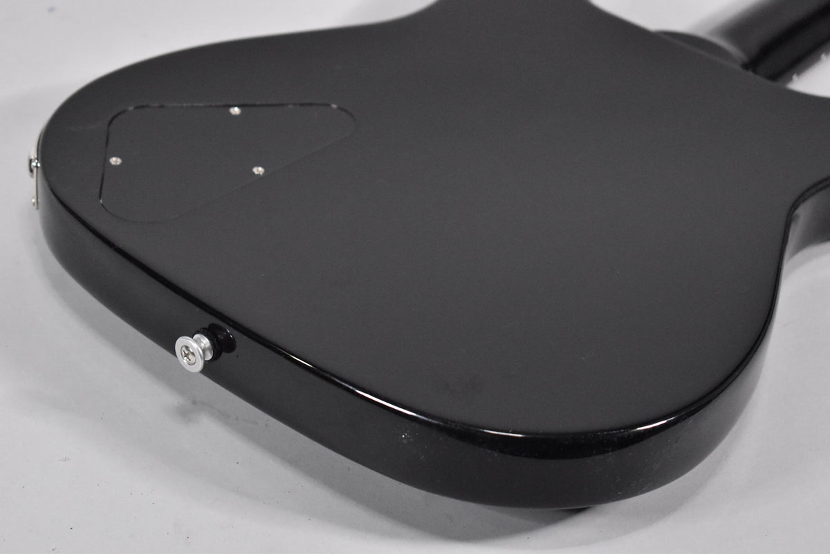 The back of the ebony guitar body, showing a matte finish with a glossy edge, a control cavity cover, and a chrome strap button.