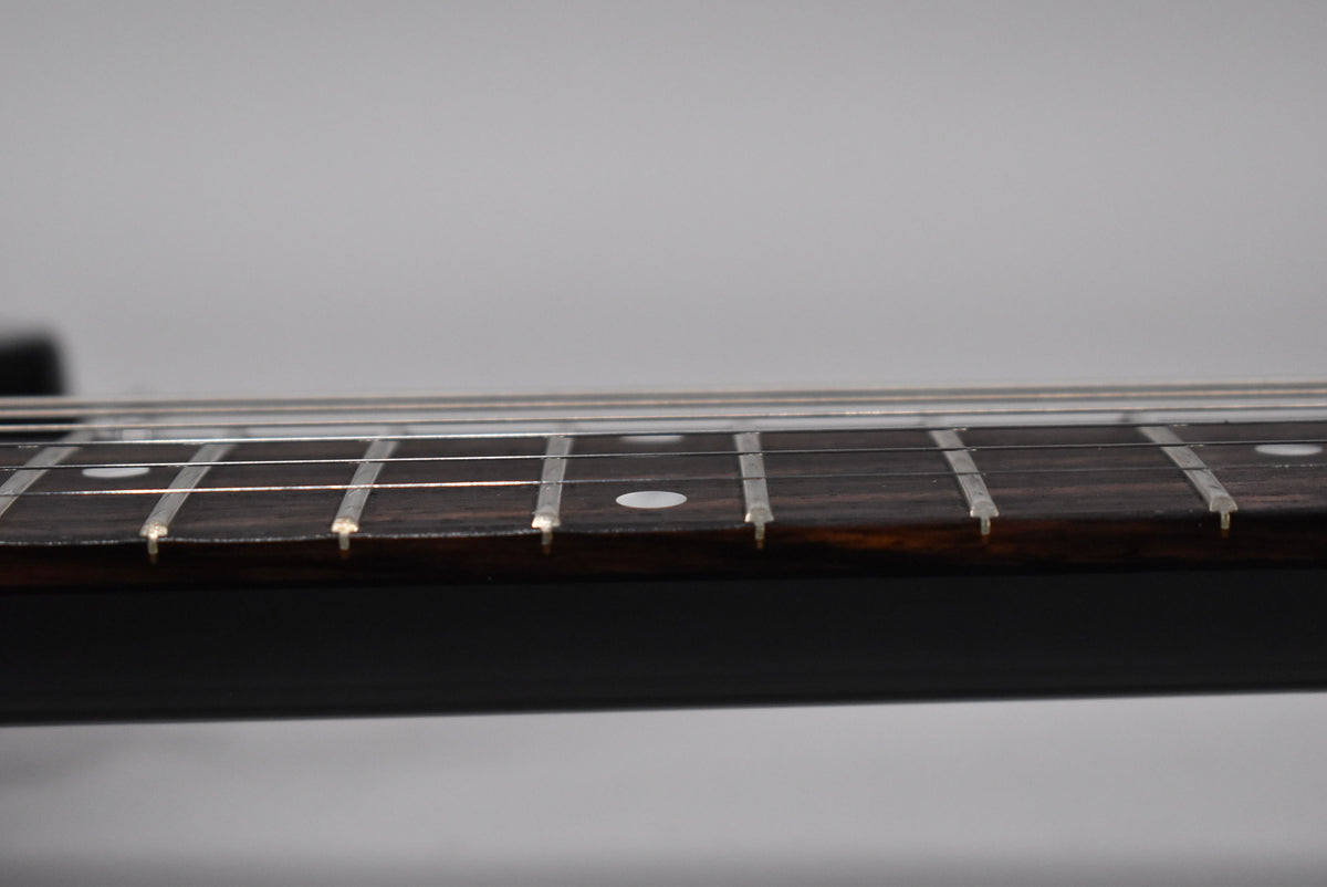 Close-up of the guitar's dark fretboard and silver frets, showing white dot inlays on the 5th and 7th frets.