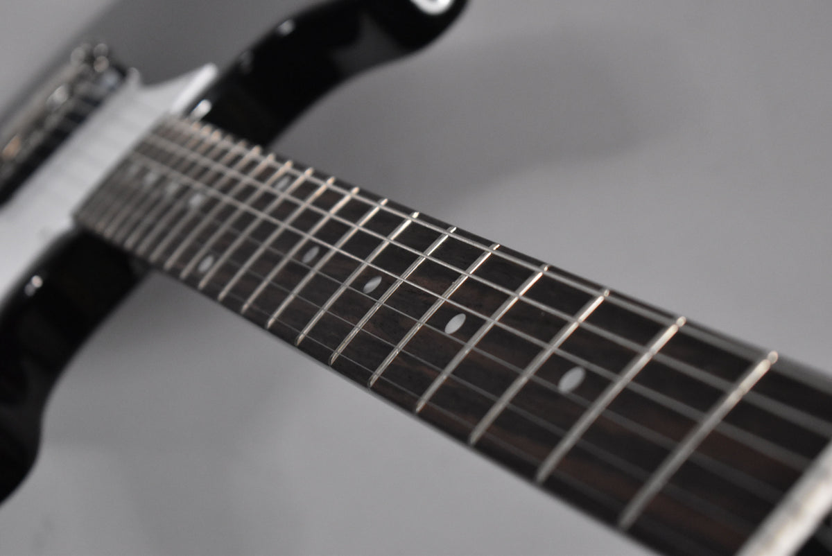 Close-up of the ebony fretboard with white dot inlays, angled from the nut towards the body, showing shiny frets.