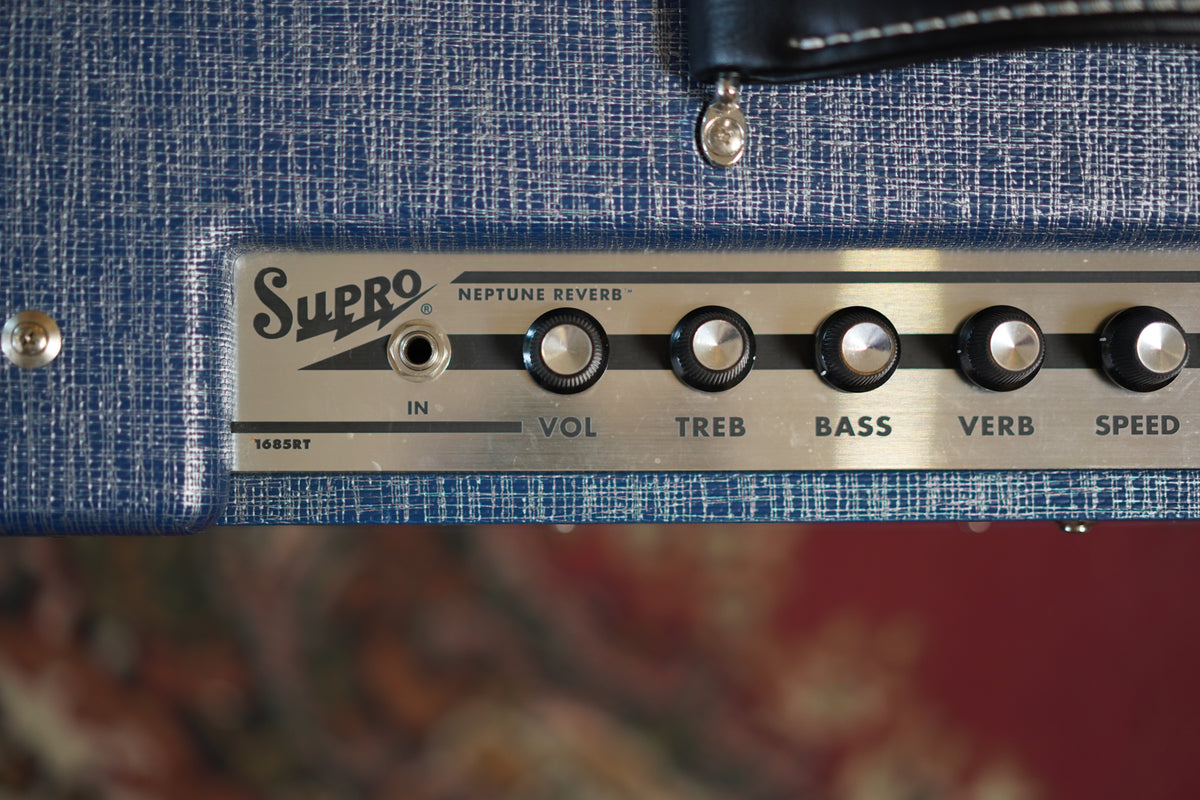 Close-up of the amp's blue textured tolex and brushed metal control panel with black knobs, showing some light wear.