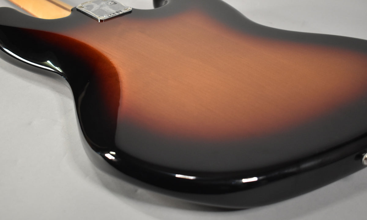 The back of the 3-Tone Sunburst Jazz Bass body, showing the glossy finish and neck plate, angled from the lower left.