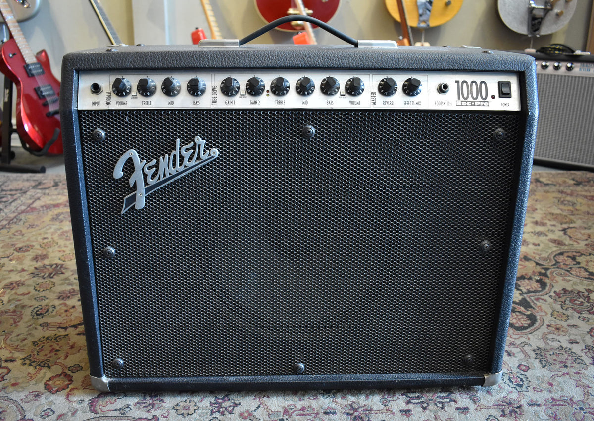 Front view of a black textured combo amp with a metal grille, silver control panel, and 14 black knobs.