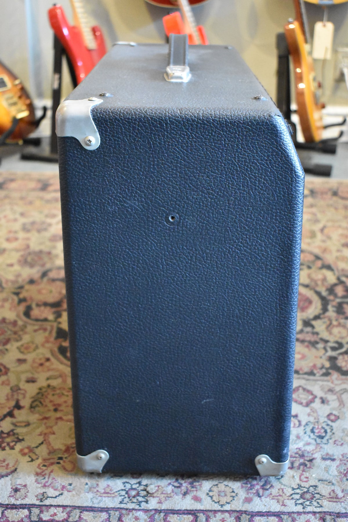 The amp is viewed from the right side, showing its black textured tolex covering, metal corner protectors, and top handle.