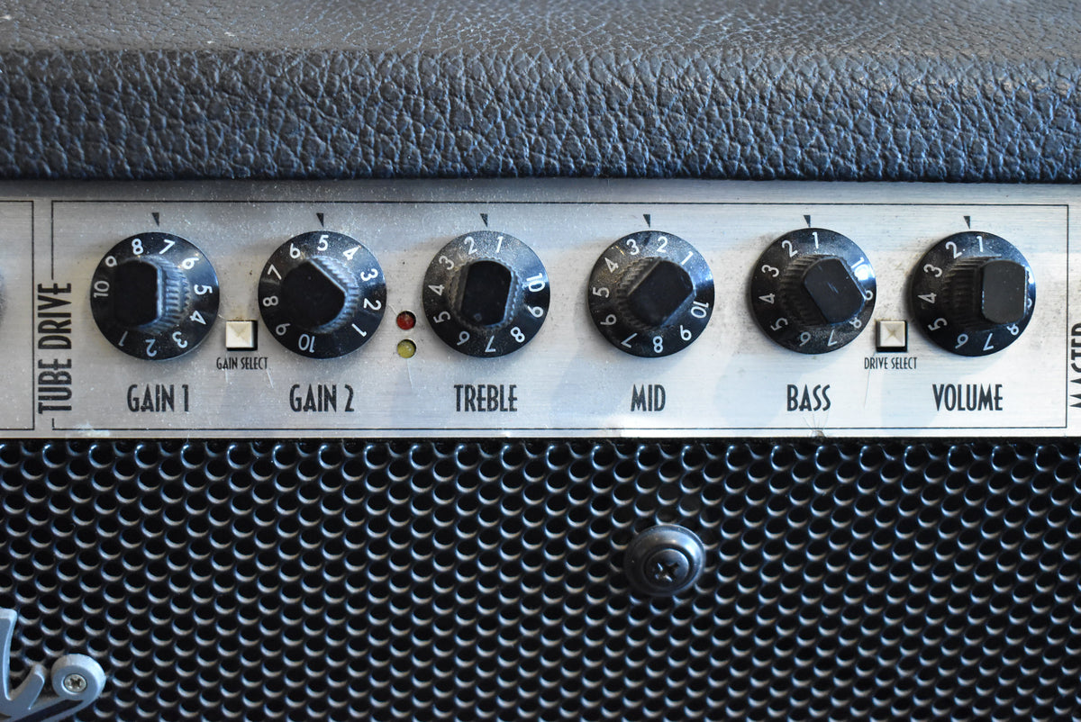 Close-up of the amp's silver control panel with six black numbered knobs, two white push-buttons, and two small indicator lights.