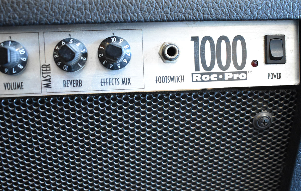 Close-up of the amp's silver control panel, showing black Volume, Reverb, and Effects Mix knobs, a footswitch jack, and a power switch.