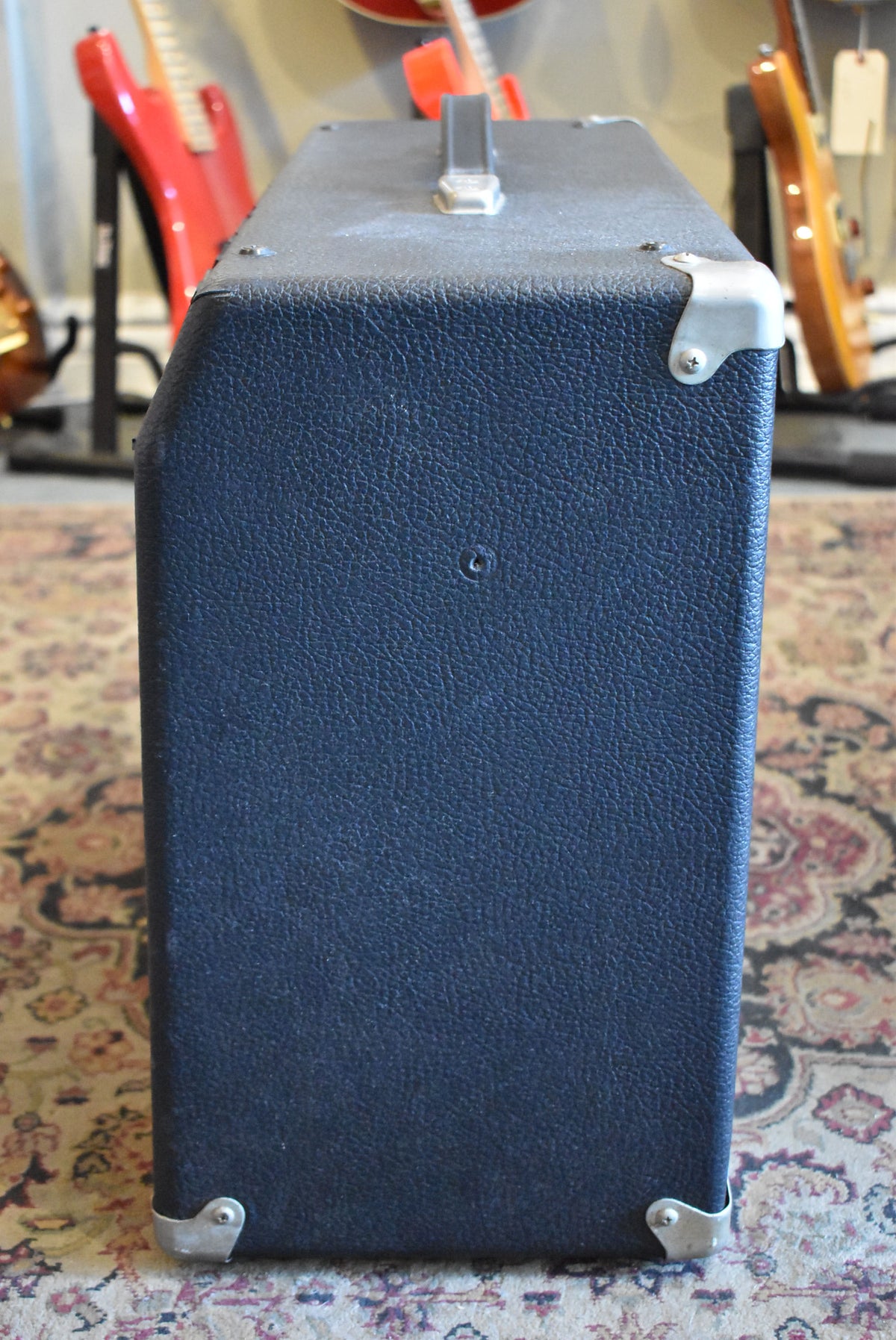 The amp's right side is shown, revealing black textured tolex, metal corner protectors, and a top handle.