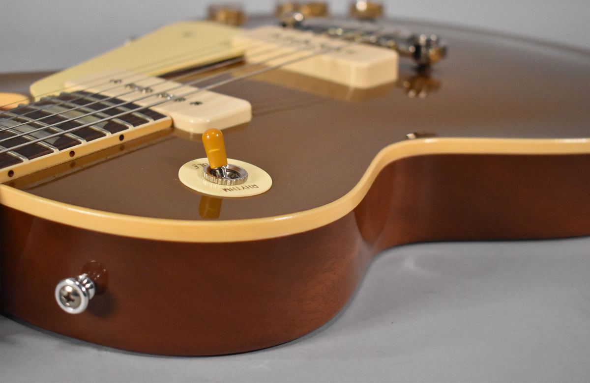 The guitar's Goldtop finish and cream binding are visible from the lower bout, with a yellow switch tip and cream pickup covers.