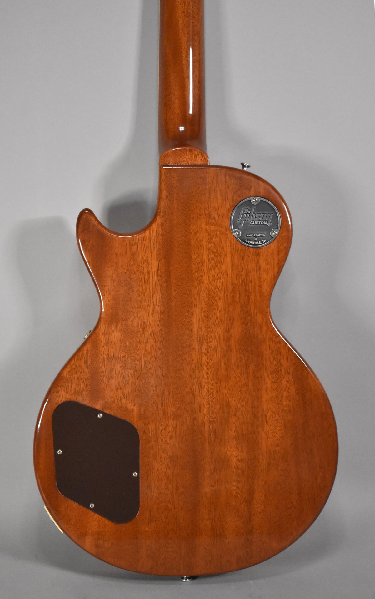 The back of a Gibson Les Paul guitar, showing the mahogany body and neck, and a "Gibson Custom" metal plate.