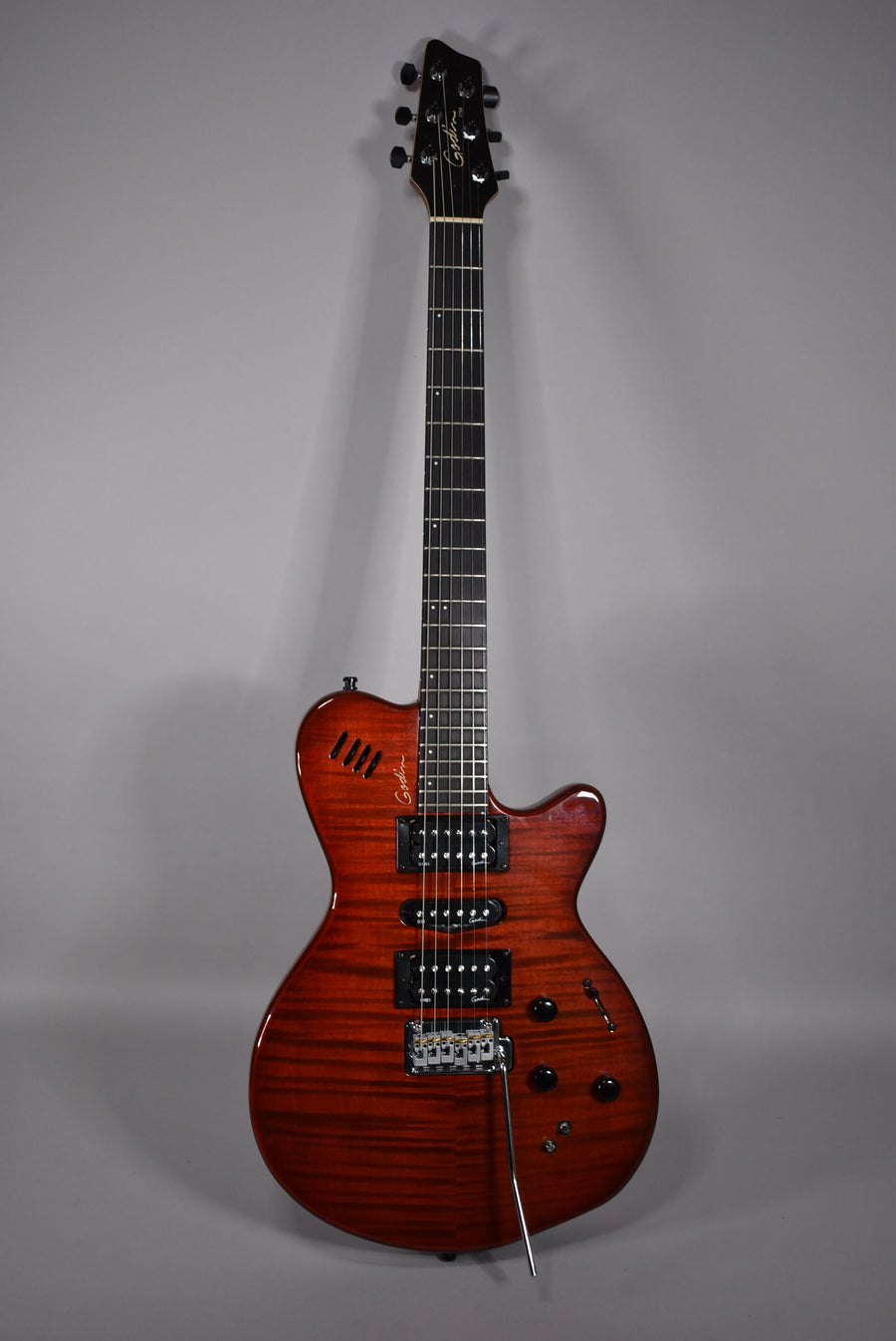Full-length view of a glossy red electric guitar with a flame maple top, black pickups, and a tremolo bridge.