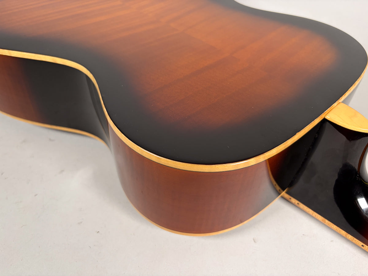 Upper bout and waist of a sunburst resonator, showing the dark brown to reddish-brown finish and light wood binding.