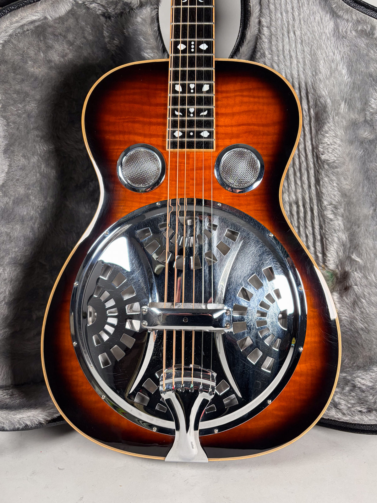 Full front view of a sunburst resonator guitar with a chrome cover plate, two round sound screens, and unique fretboard inlays.