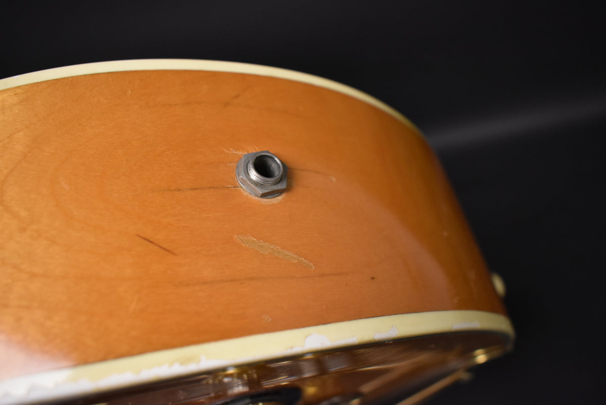Close-up of the guitar's lower bout, showing the input jack, natural finish, and visible wear, scratches, and binding deterioration.