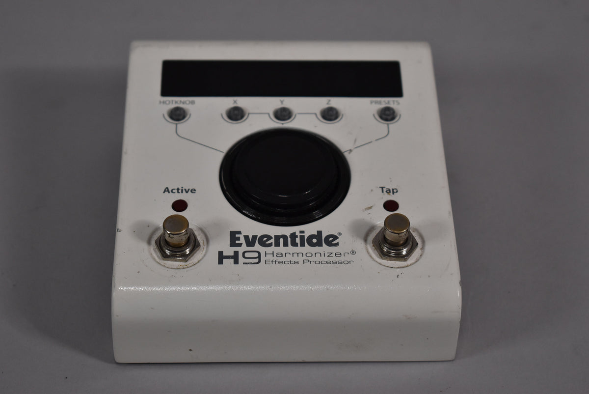 White pedal with a large black central knob, two footswitches, and a display, showing minor scuffs and wear.