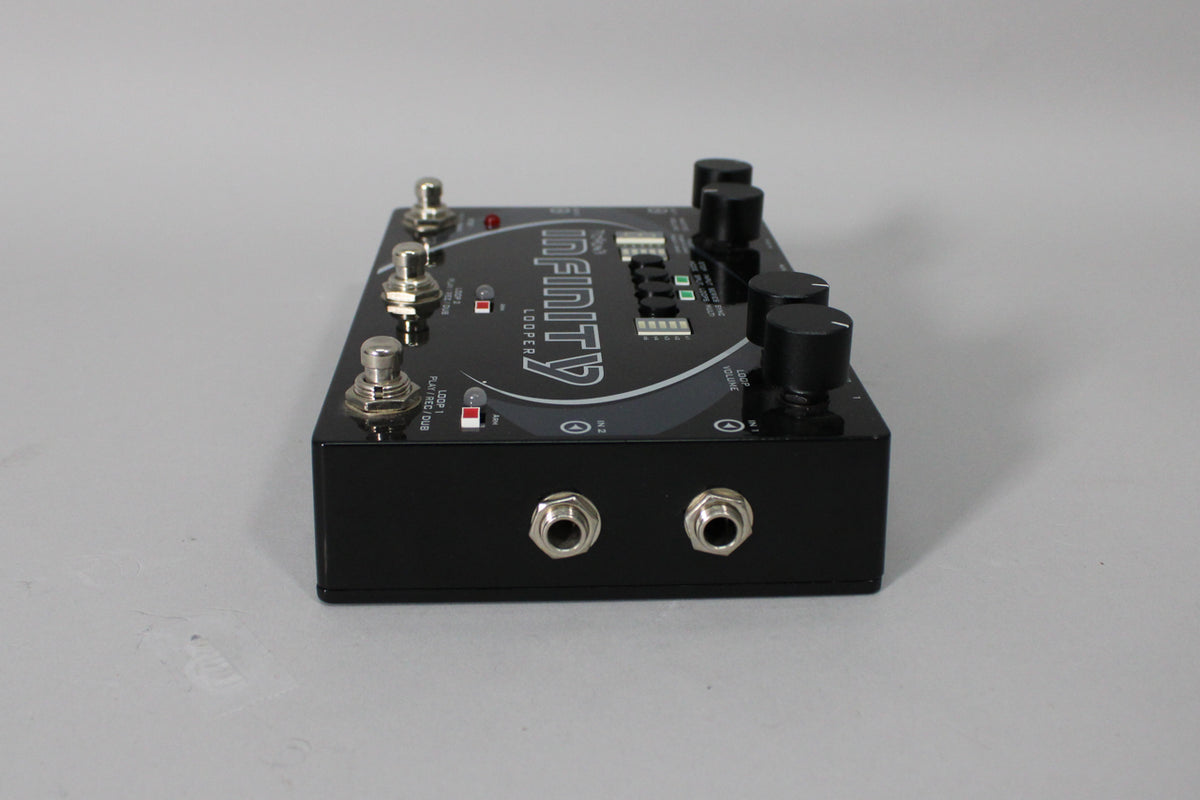 A black stereo looper pedal, viewed from the front-left, showing three footswitches, four knobs, and two input jacks.