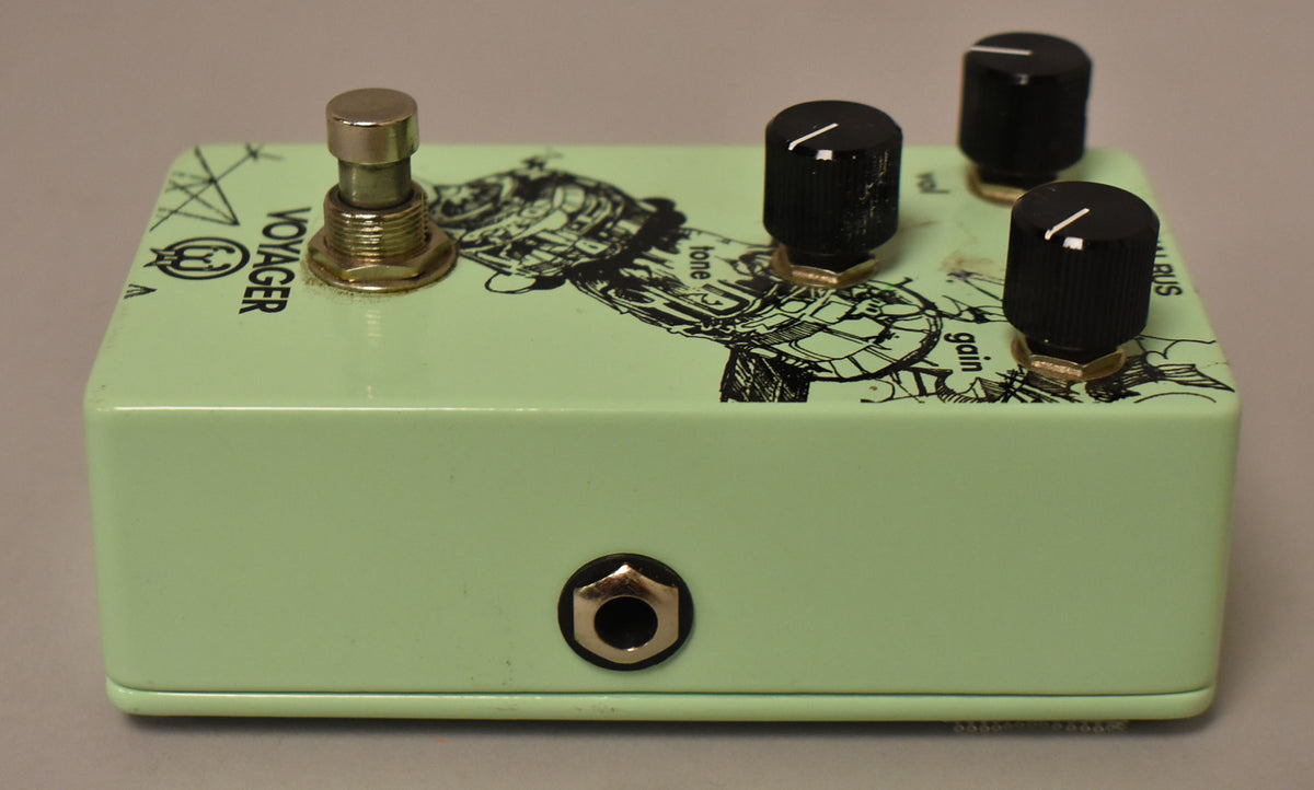 The green effect pedal is angled, showing the input jack on the front, a footswitch, and three black control knobs on top.