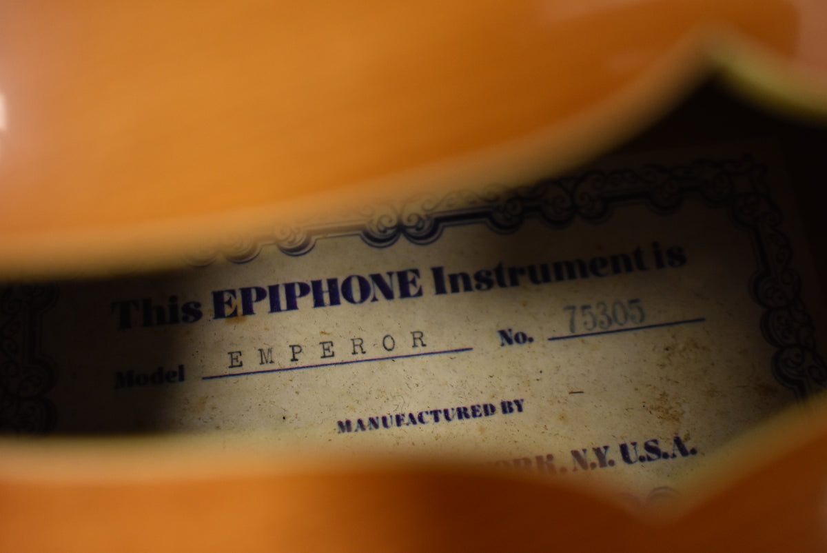 A close-up of the guitar's interior label, showing "This EPIPHONE Instrument is Model EMPEROR No. 75305" on aged, slightly stained paper.