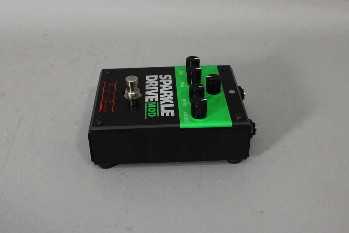 A black pedal with a bright green stripe on the right, showing a silver footswitch and four black control knobs.