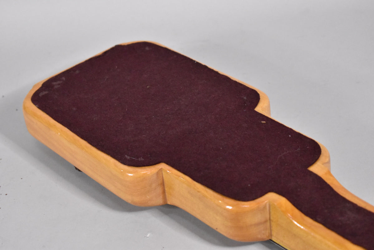The back of the lap steel shows a light wood finish with a dark red felt pad, revealing some wear and dust on the felt.