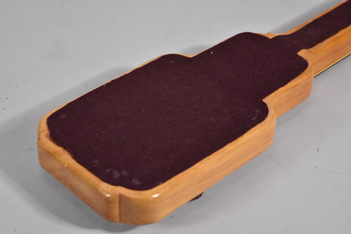 The underside of the lap steel, showing its light wood body with a dark maroon felt pad covering the majority of the back.