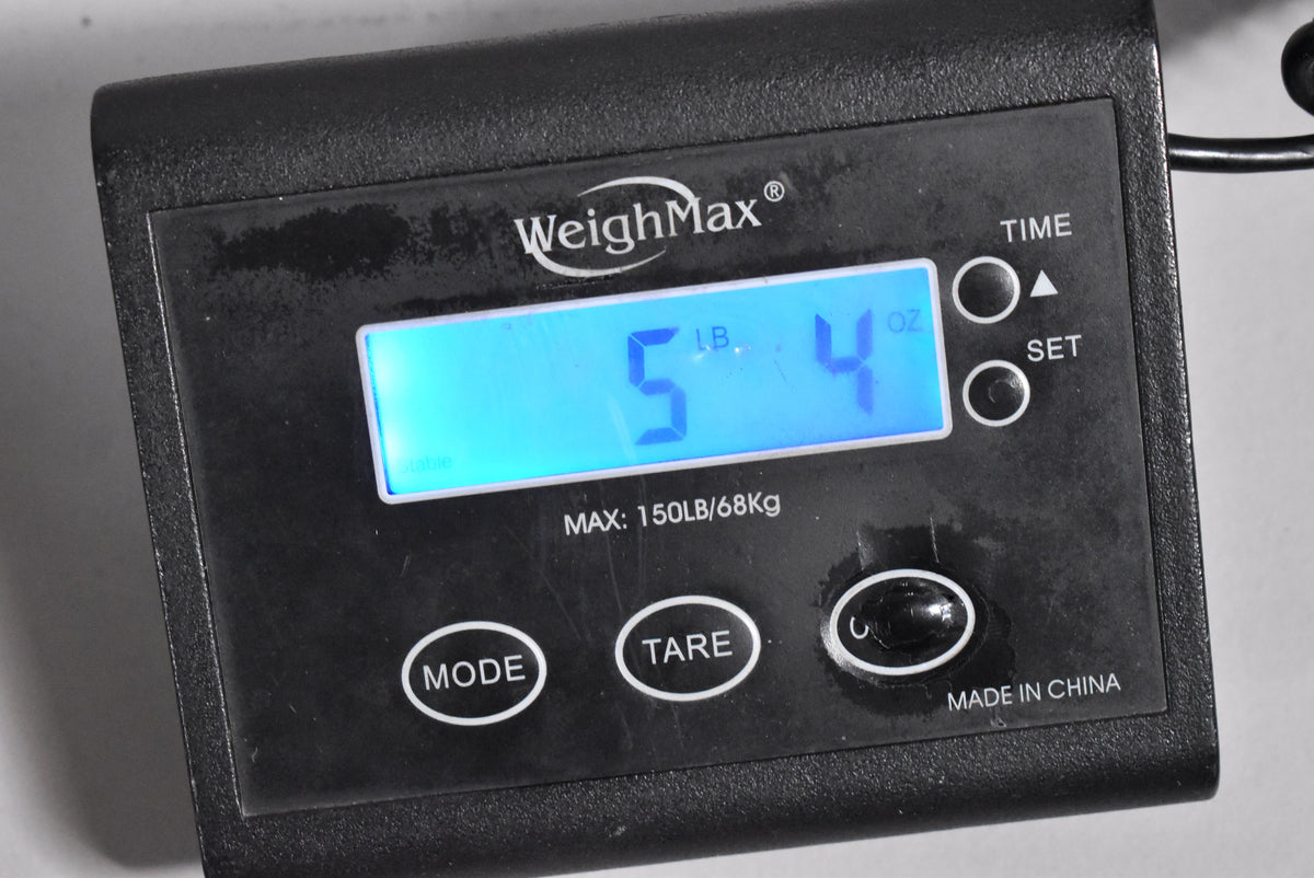 A close-up of a black digital scale displaying "5 LB. 4 OZ." in blue, with "WeighMax" and "MADE IN CHINA" visible.